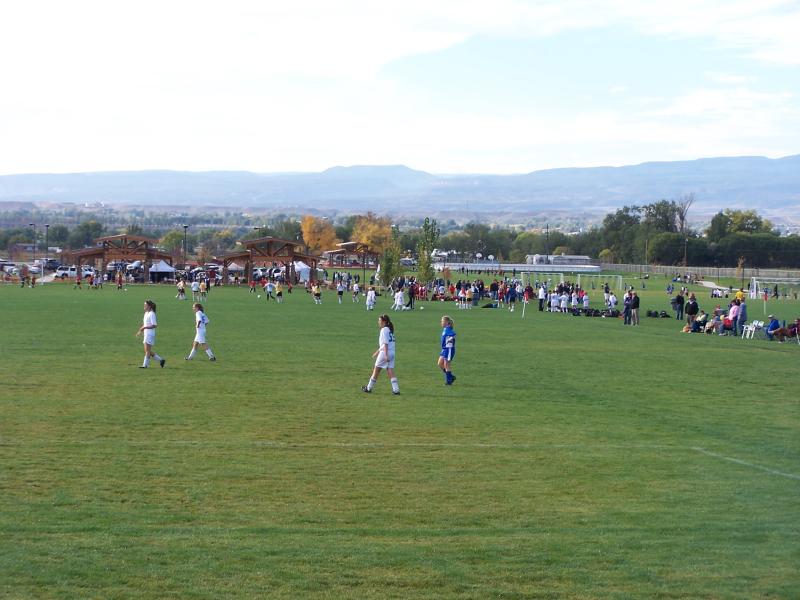 Children in uniform playing soccer games on the grassy field.